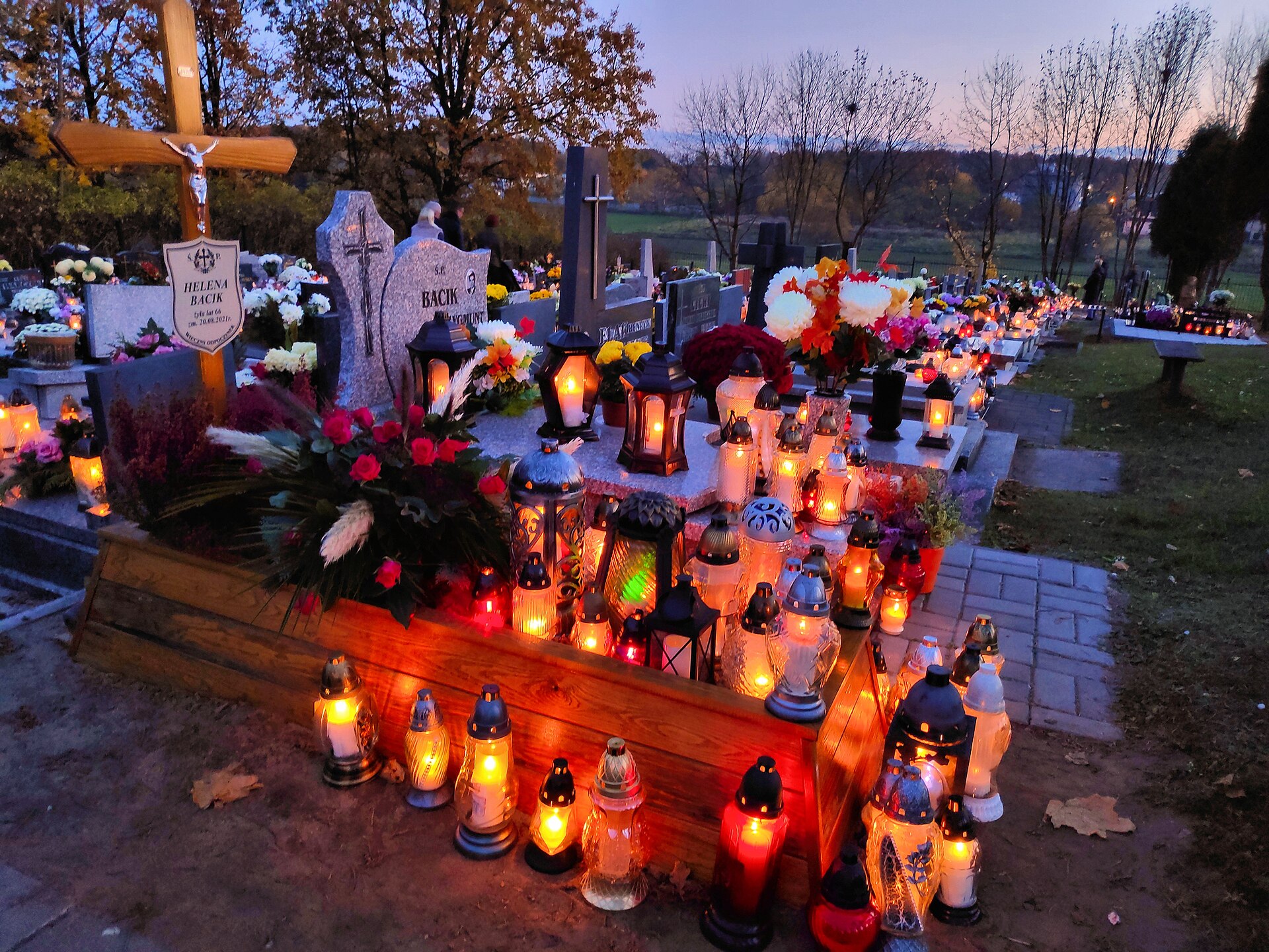 Znicze i kwiaty na grobach w Dzień Wszystkich Świętych o zmierzchu